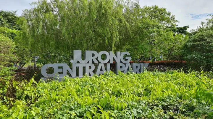 A calm dog on a leash standing on a quiet park path at Jurong Central Park in Jurong East / Boon Lay, Singapore, lush tropical greenery and soft afternoon light.