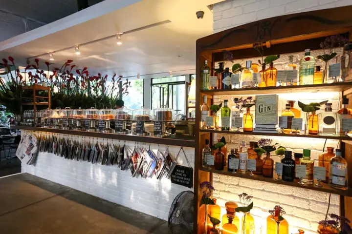 Existing PS.Cafe Harding bar photograph, showing bottles, flowers and cake displays; not a current renovation photograph.
