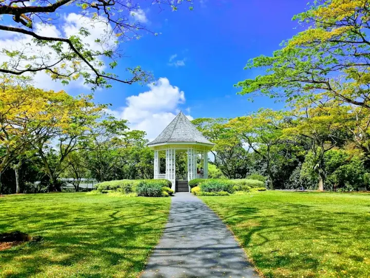 A path crosses the lawn towards the Bandstand pavilion at Singapore Botanic Gardens.