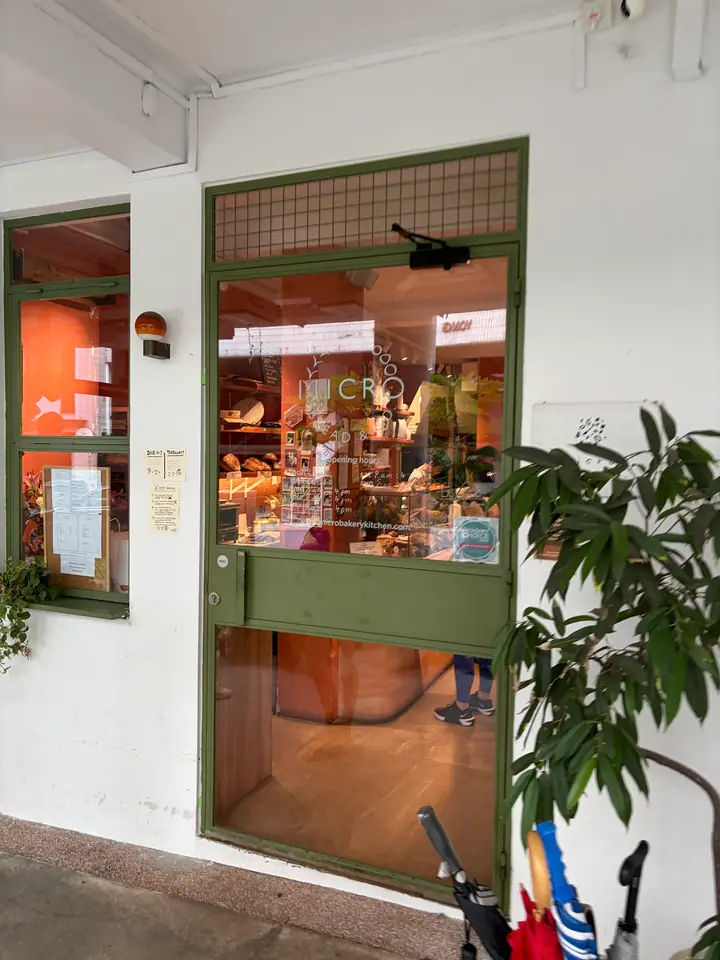 Green-framed glass doors and windows bearing MICRO bakery signage, with bread visible inside.